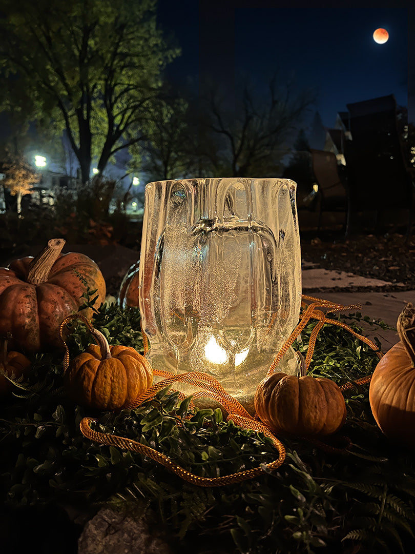 A fluted ice lantern looks charming nestled with pumpkins on a crisp autumn night.